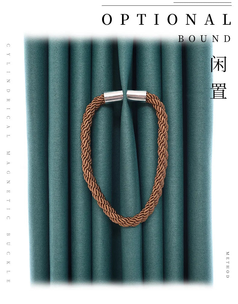 A close-up shot of a brown rope magnetic curtain tieback with a silver buckle clasp against a teal fabric background.