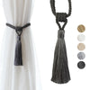 A set of two dark gray tassel curtain tiebacks with braided cord for holding fabric.