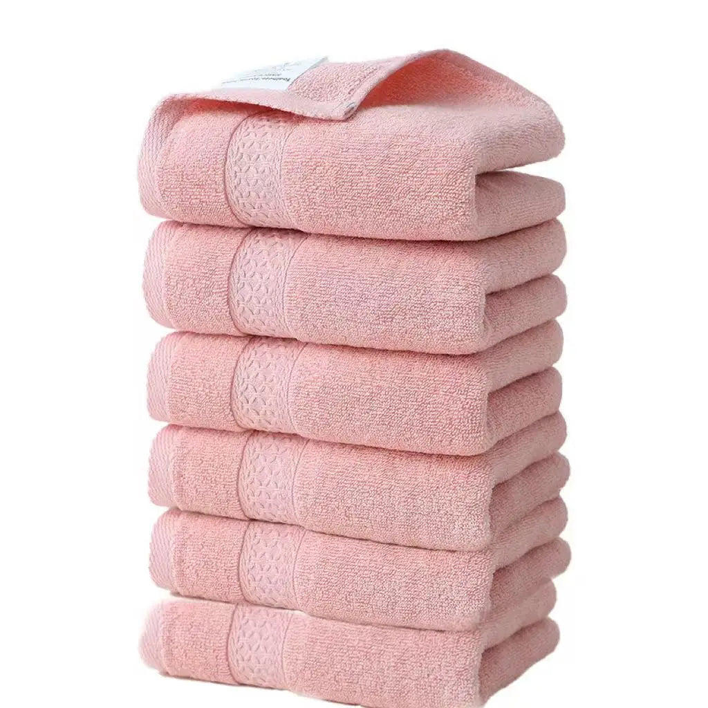 A stack of six pink, textured face towels made of premium pure cotton.