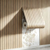 A roll of wood grain peel-and-stick wall tiles is partially unrolled against a vertical wooden slat background.