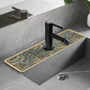 A matte black faucet mounted on a gray countertop with a floral patterned mat.