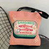 A pink canvas tote bag featuring a graphic print of sardines and text indicating the establishment date.