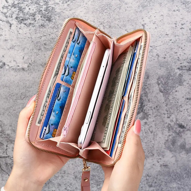 A hand holds an open pink PU leather wallet with multiple card slots and a smartphone inside.