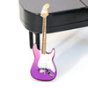 A pink and white electric guitar is displayed on a black piano bench.