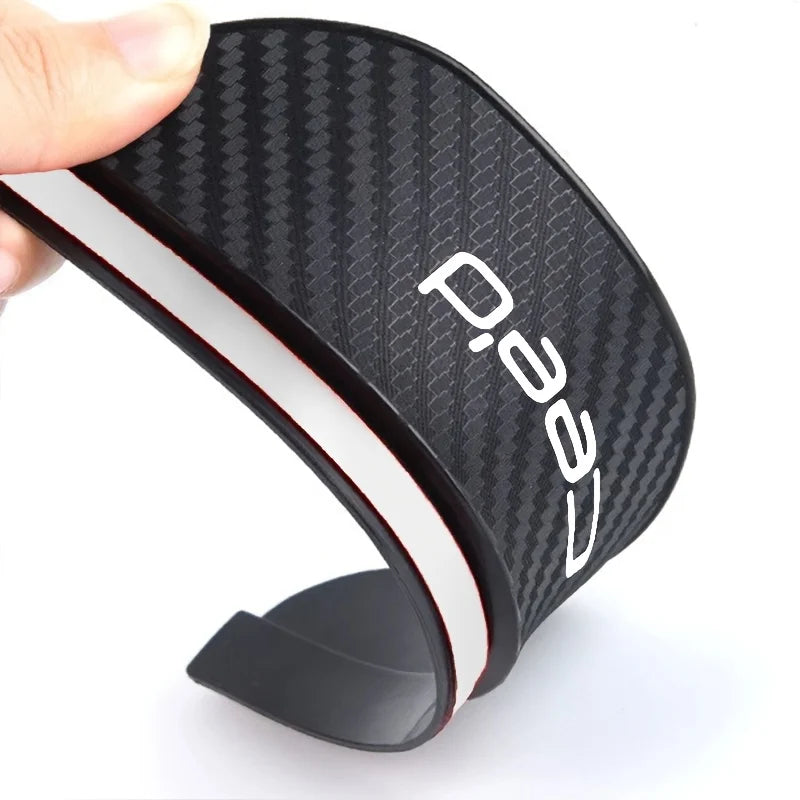 A matte black carbon fiber rearview mirror rain guard with a white trim is shown from the side.
