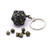 A black metal die with gold numbers is attached to a silver ring, alongside several loose dice.