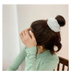 A woman ties her dark hair with a white plush coil hair tie.