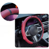 Close-up view of a pink perforated leather steering wheel cover on a car's steering wheel.
