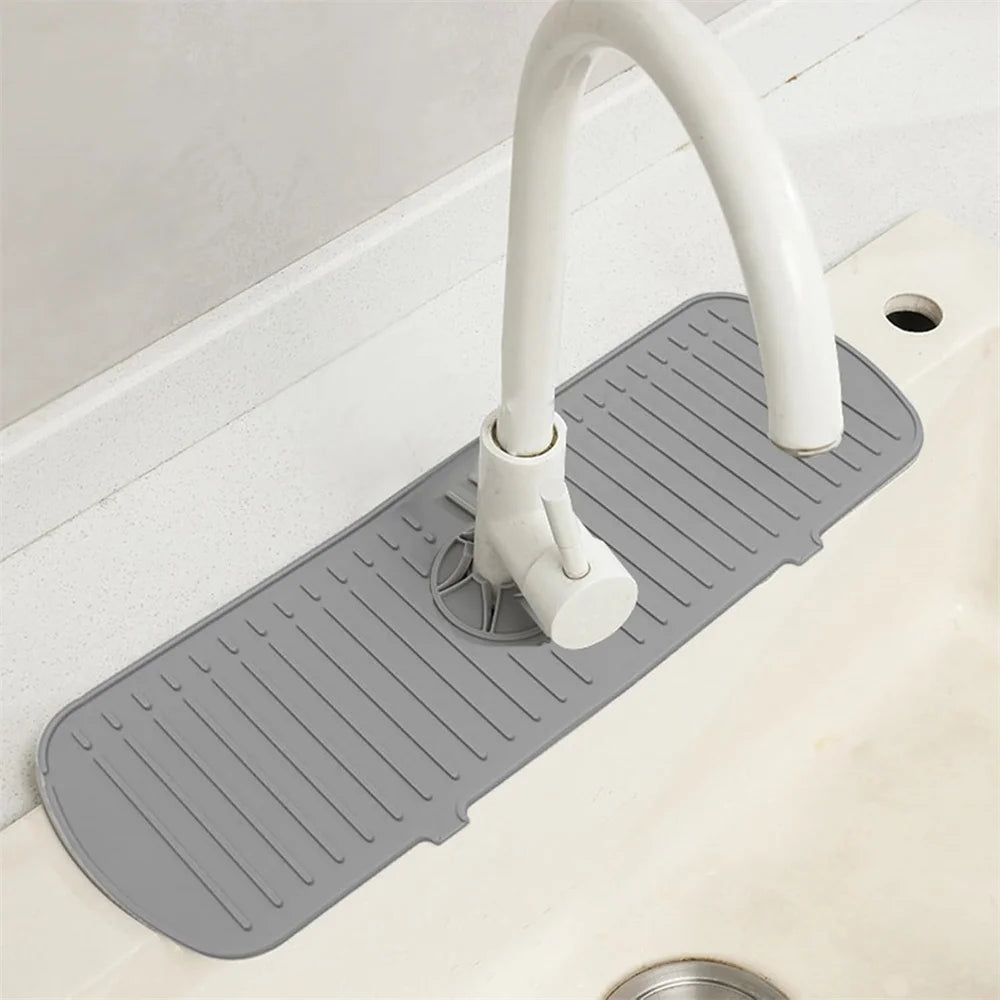 A silicone faucet drain mat with a curved spout is placed on a white countertop.