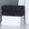 A stack of dark gray and white microfiber bath towels on a white surface.