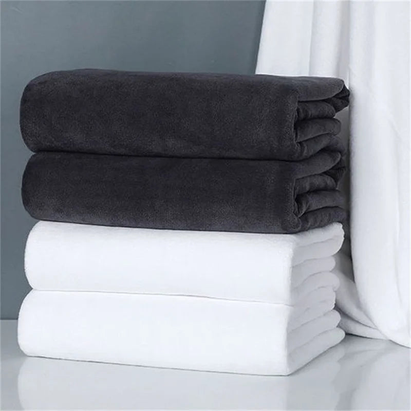 A stack of dark gray and white microfiber bath towels on a white surface.