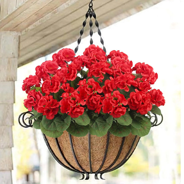 A hanging basket filled with bright red artificial geranium flowers and green leaves.
