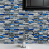 A close-up of a gray and blue marble tile backsplash with a modern chrome faucet installed on a white countertop.