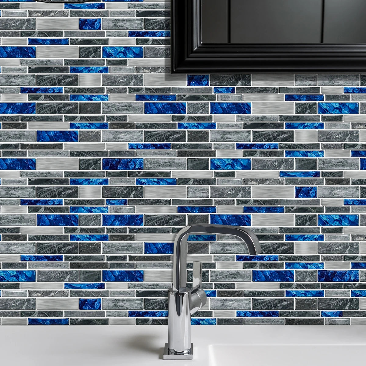 A close-up of a gray and blue marble tile backsplash with a modern chrome faucet installed on a white countertop.