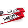 Red and white striped fabric ribbon with black text reading SLOW CAR CLUB and Japanese characters on a nylon keychain.