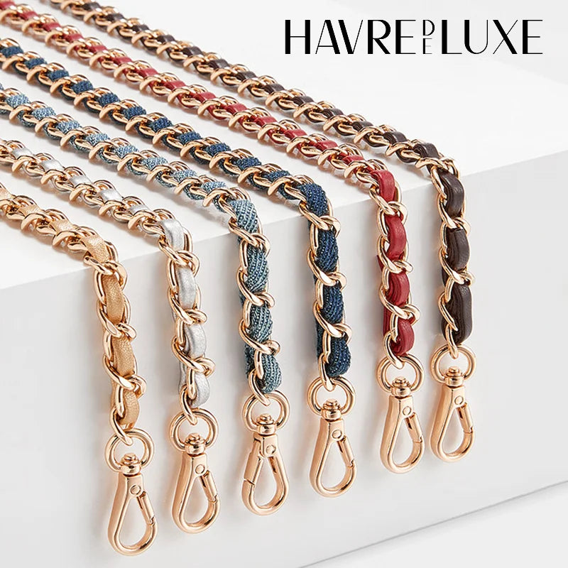 Multiple strands of braided metal chains in gold, copper, and blue are displayed on a white surface.
