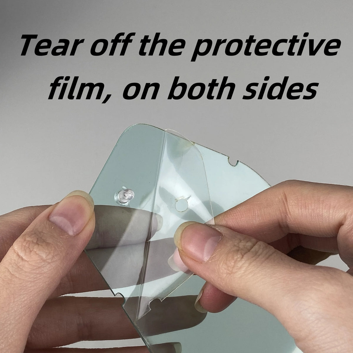 Hands tear off a protective film from an anti-fog lens on motocross goggles.