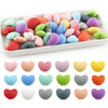 A collection of ten silicone heart beads in various pastel and bright colors arranged on a white tray.