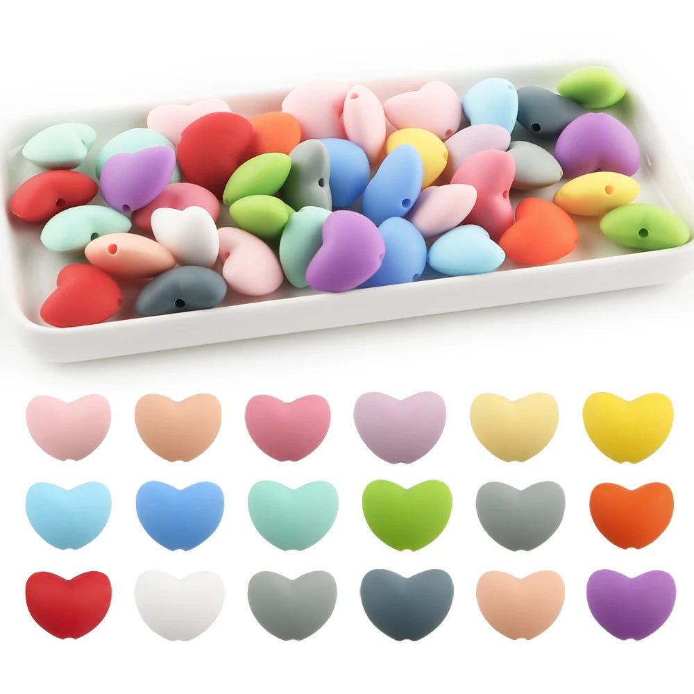 A collection of ten silicone heart beads in various pastel and bright colors arranged on a white tray.