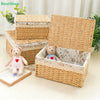A stack of handwoven rattan storage baskets, including a large open basket and smaller ones, with a stuffed bear toy inside.