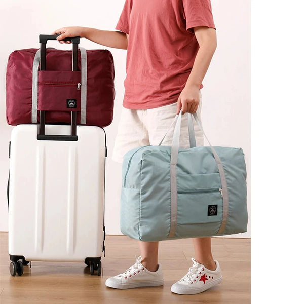 Eine Person hält einen weißen Rollkoffer und eine hellblaue Nylon-Reise-Tasche.
