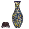 A blue and yellow floral ceramic vase with a narrow neck and bulbous body, displayed on a dark wooden stand.