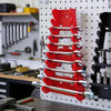 A red and silver heavy-duty wrench organizer tray with multiple slots is mounted on a white pegboard.