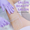 A hand wearing a purple nitrile glove is applying a clear, flexible bandage to a person's arm.