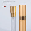 A clear glass atomizer bottle with a gold-colored cap and a matching cylindrical aluminum body.