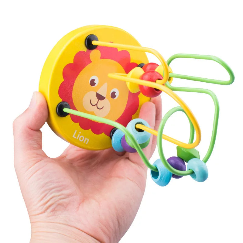 A hand holds a wooden bead maze roller coaster toy featuring a lion design and colorful beads.