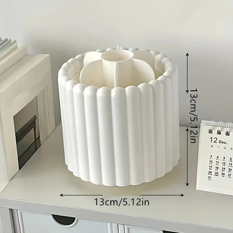 White rotating makeup brush organizer with removable compartments sitting on a light-colored surface.