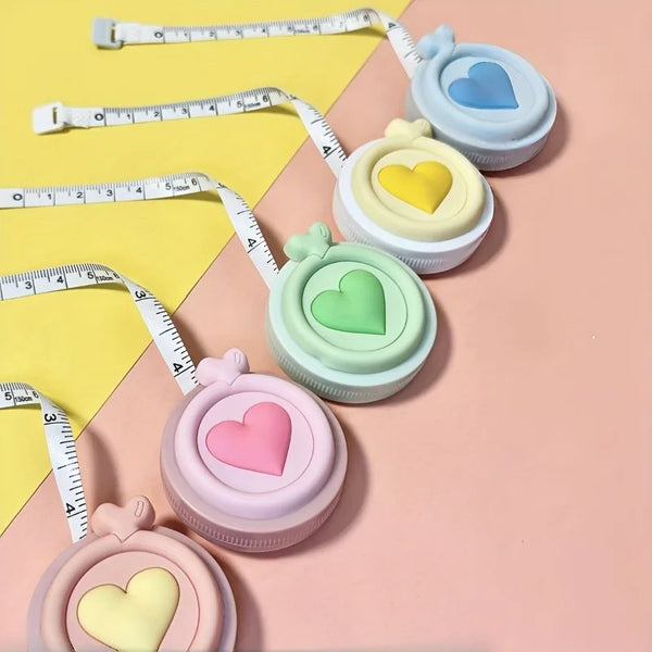 A collection of pastel heart-shaped retractable tape measures in various shades of pink, yellow, and green.