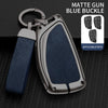 A matte gun blue buckle key case with a silver finish and dark blue leather strap, shown next to applicable keys.