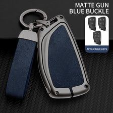 A matte gun blue buckle key case with a silver finish and dark blue leather strap, shown next to applicable keys.