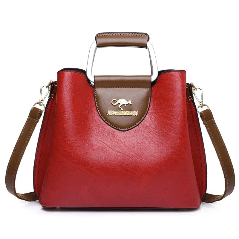 A red leather vintage crossbody tote bag with brown trim and a leather handle.
