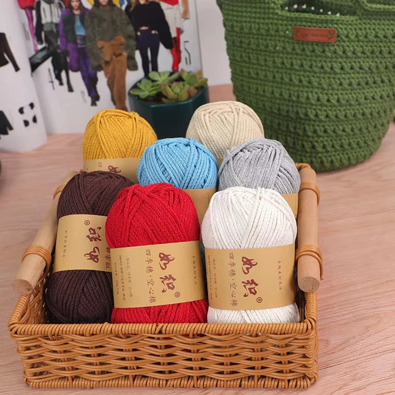 A collection of various colored crochet yarn skeins in a wooden basket, including red, blue, gray, and cream shades.