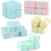 A set of colorful Infinity Magic Cubes in pink, light blue, and yellow stacked and scattered.