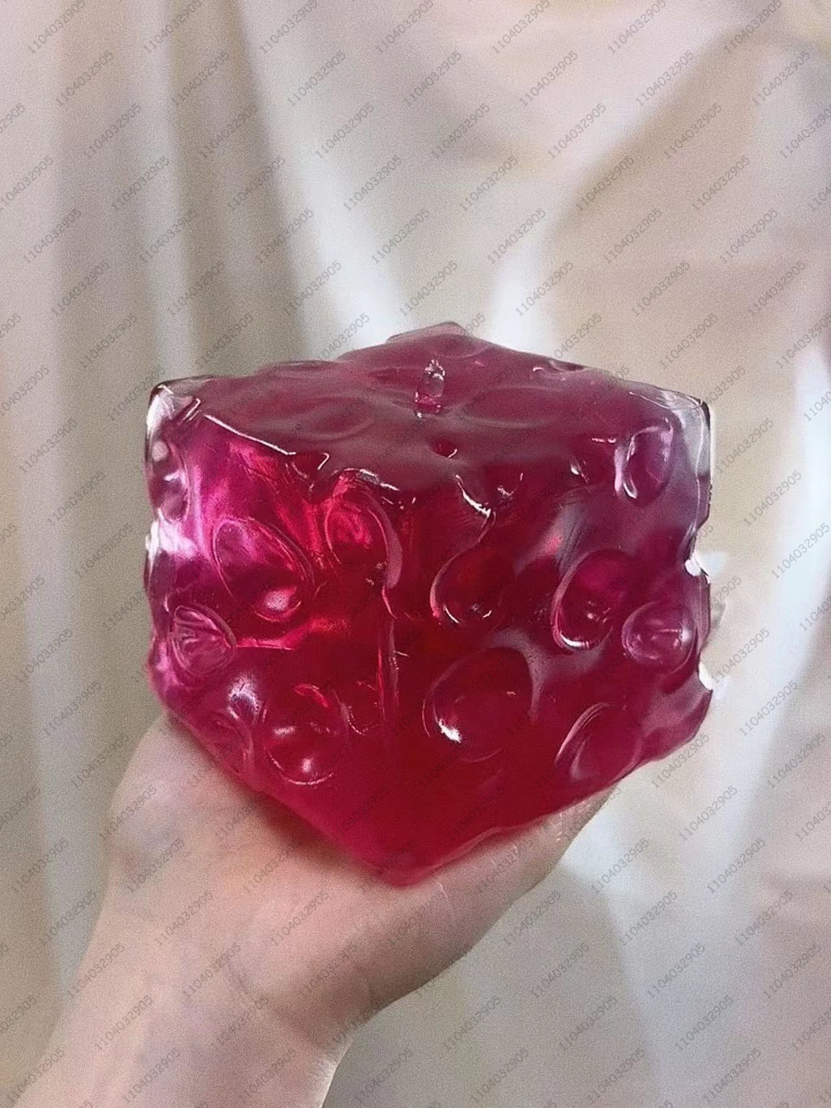 A translucent magenta frosted matte jumbo cheese stress ball held in a hand against a white background.
