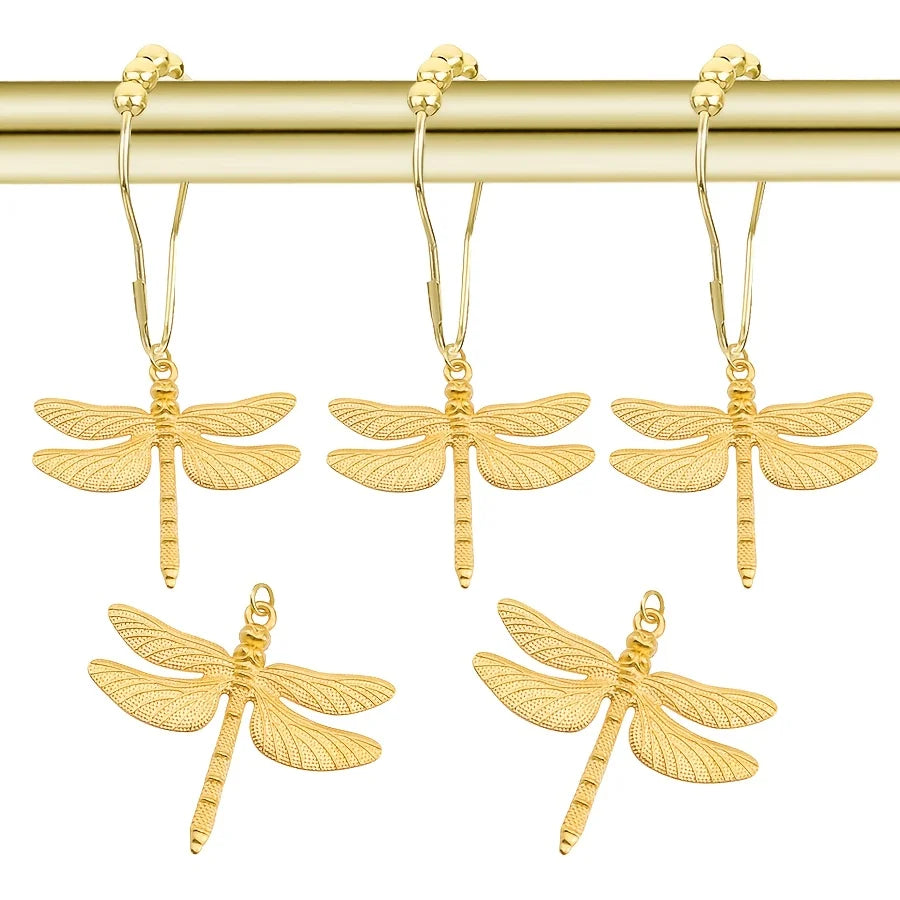 A set of twelve gold-colored dragonfly shower curtain hooks hanging from a brass rod.
