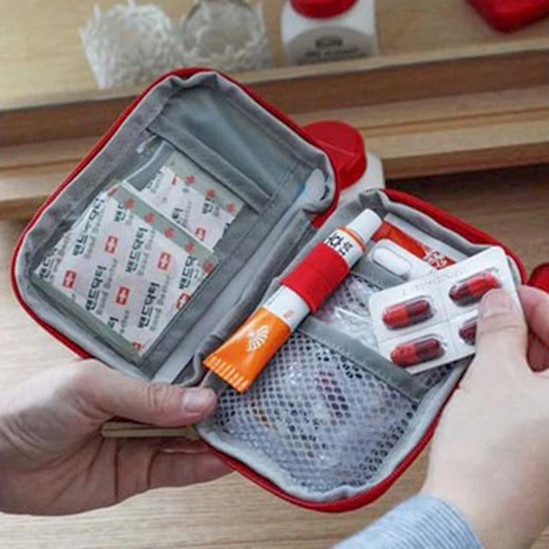 A hand opens a red travel medicine organizer bag revealing compartments for medical supplies.