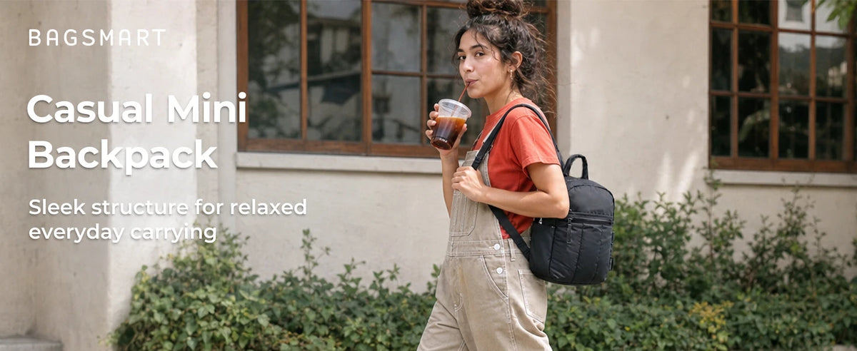 A woman wearing a red shirt and overalls carries a black mini backpack while holding a drink outdoors.
