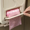Eine Hand zieht einen rosa Plastiksack Müll aus einem weißen, hängenden, klappbaren Küchen- und Campingmülleimer.