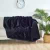 A black faux fur throw blanket draped over a white sofa next to a potted green plant.