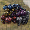A pile of 15 polyhedral dice in various colors and sizes scattered on a tiled surface.
