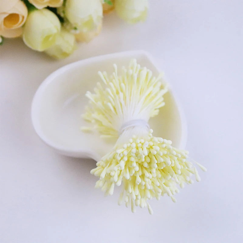 A white ceramic dish holds a cluster of pale yellow pearl flower stamens for DIY crafts and wedding decor.
