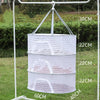 A white folding hanging drying net with mesh protection is suspended from a metal frame outdoors.