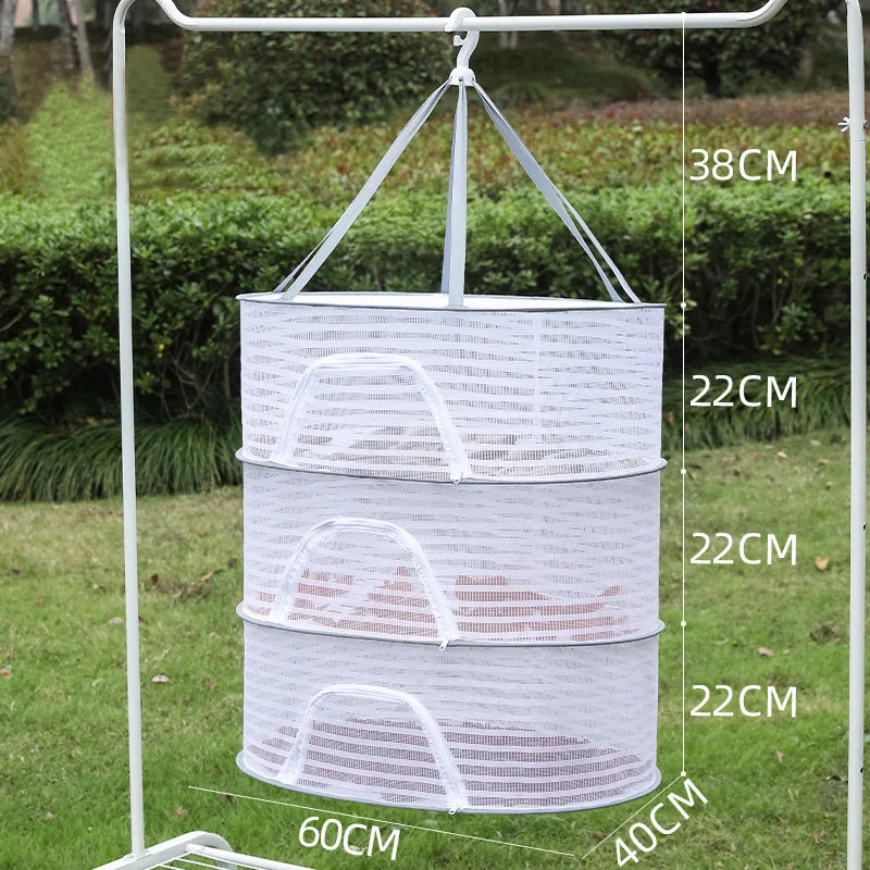 A white folding hanging drying net with mesh protection is suspended from a metal frame outdoors.