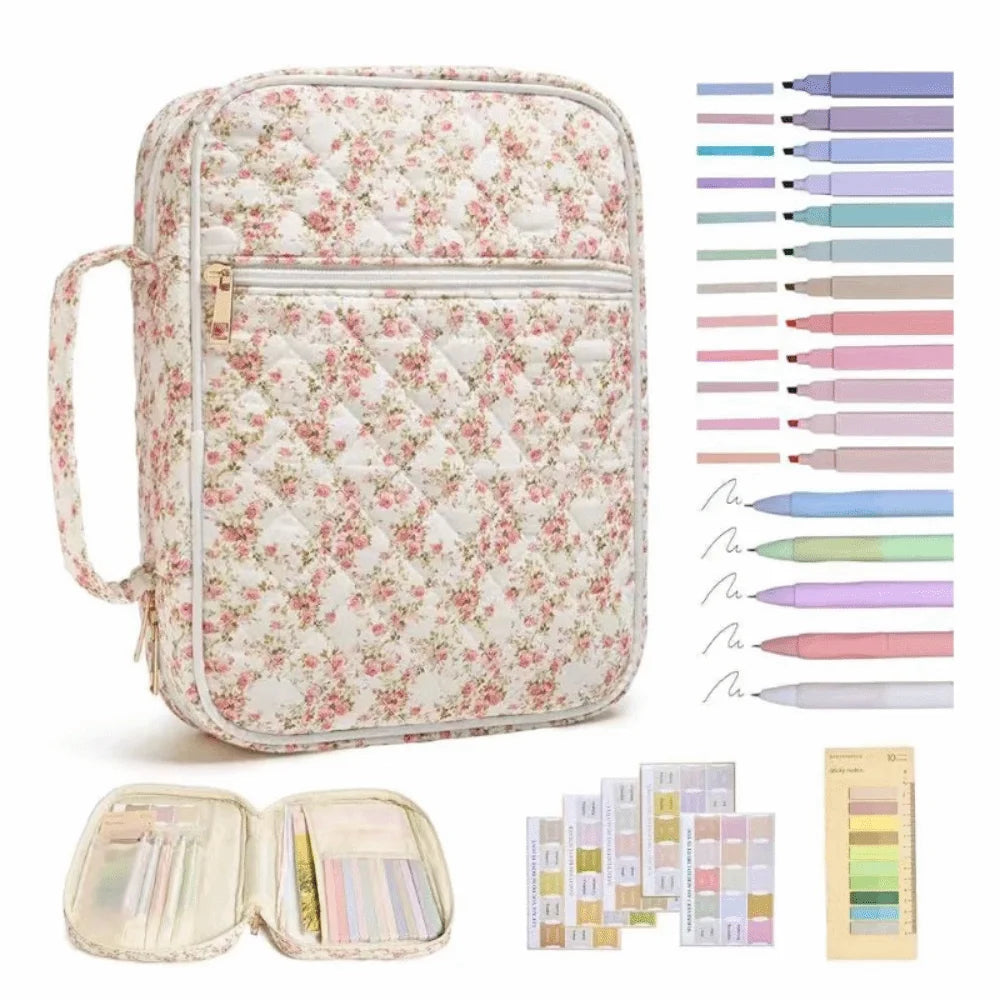 A floral quilted Bible cover with a zipper pocket and carry handle shown next to various colored pens and a palette.