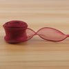 A roll of deep red satin ribbon, 40mm wide, lying on a wooden surface.