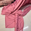 A draped piece of pink satin fabric is shown, folded and flowing on a white surface.